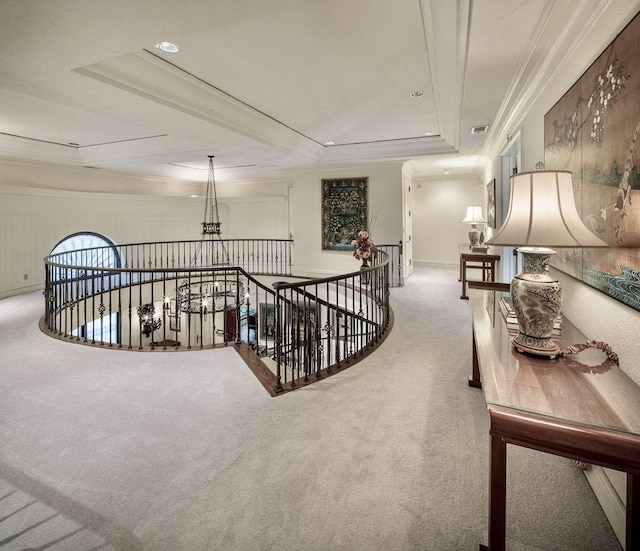 hall featuring carpet flooring, a tray ceiling, and crown molding