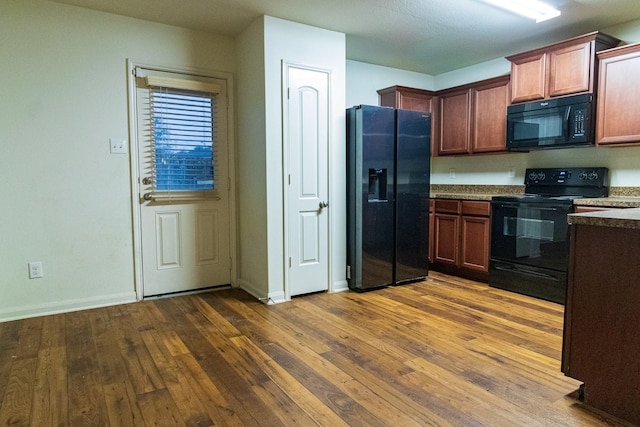 kitchen featuring black appliances and dark hardwood / wood-style flooring