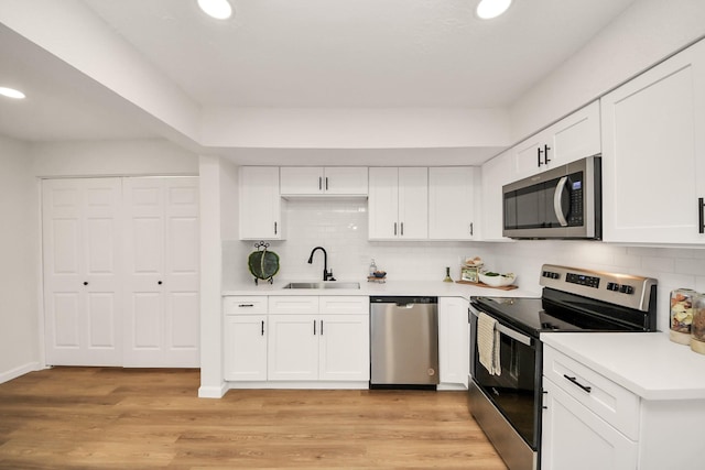 kitchen with white cabinets, backsplash, sink, and stainless steel appliances