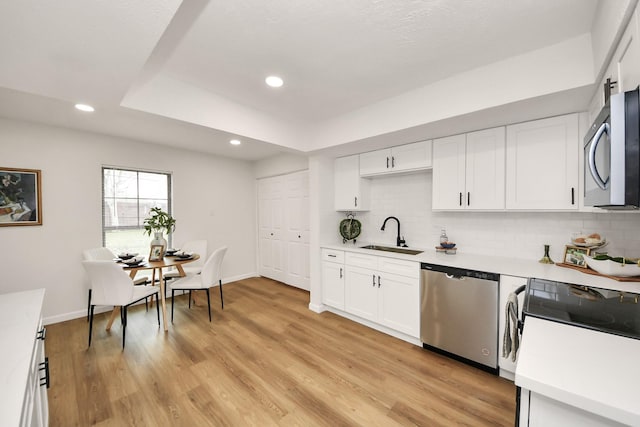 kitchen with backsplash, stainless steel appliances, sink, light hardwood / wood-style flooring, and white cabinets