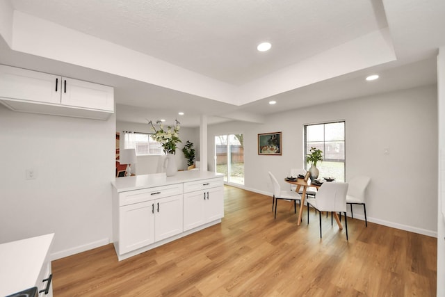 dining room featuring a tray ceiling and light hardwood / wood-style flooring