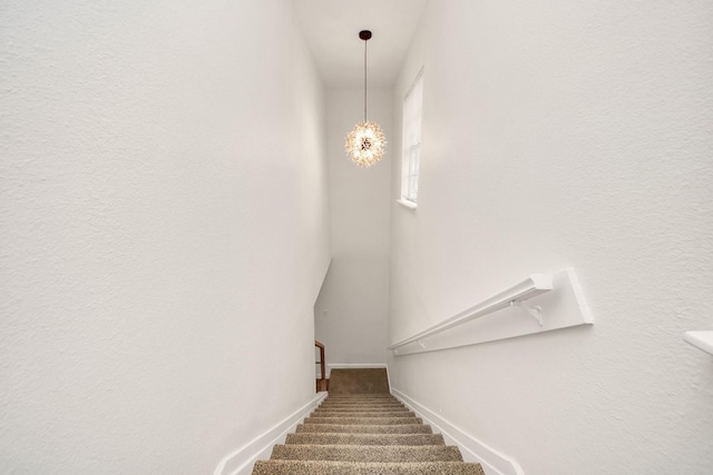 stairway featuring a notable chandelier