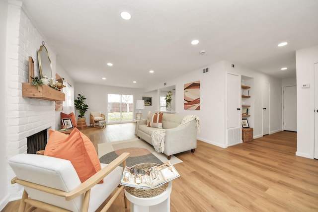 living room with light hardwood / wood-style floors and a brick fireplace