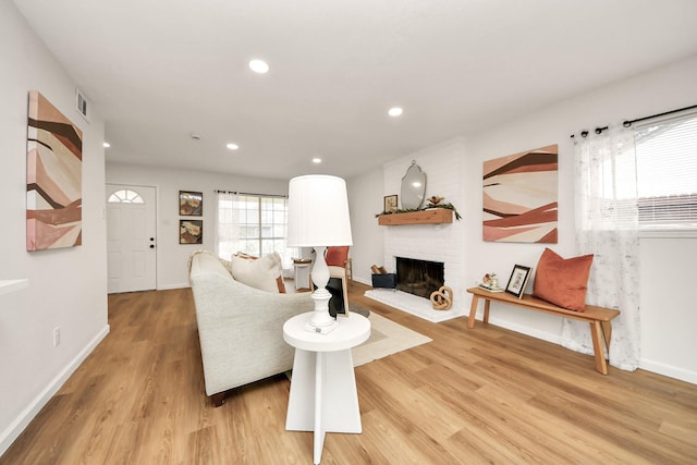 living room with light hardwood / wood-style flooring and a brick fireplace