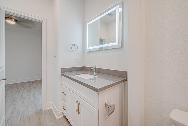 bathroom featuring ceiling fan, hardwood / wood-style floors, vanity, and toilet