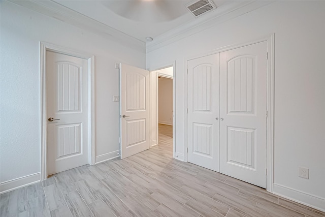 unfurnished bedroom with a closet, ornamental molding, ceiling fan, and light hardwood / wood-style flooring