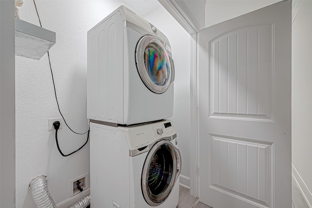 washroom featuring stacked washer / drying machine and light tile patterned floors