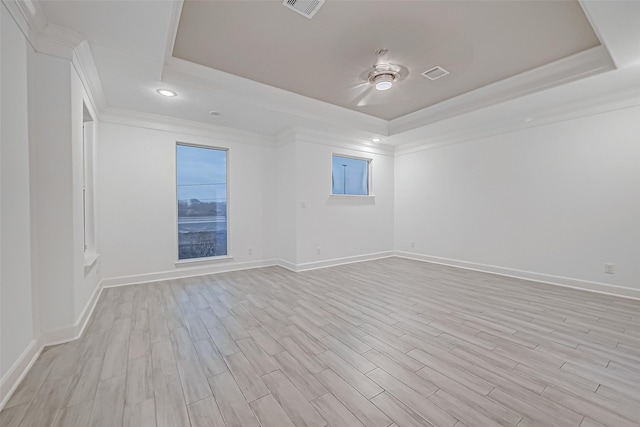 unfurnished room with crown molding, light wood-type flooring, and a raised ceiling