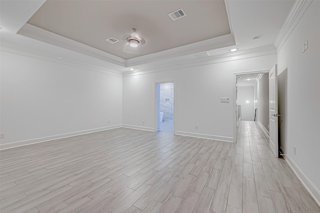 unfurnished room featuring crown molding, light hardwood / wood-style flooring, and a raised ceiling