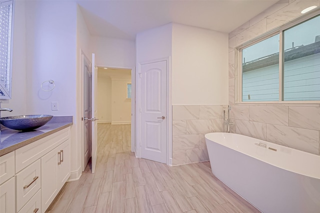 bathroom featuring vanity, tile walls, hardwood / wood-style floors, and a tub