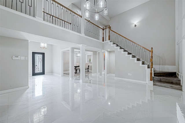 interior space featuring an inviting chandelier, a towering ceiling, and decorative columns