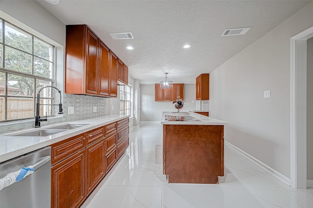 kitchen featuring dishwasher, sink, tasteful backsplash, a textured ceiling, and a kitchen island