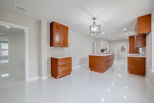 kitchen with pendant lighting, backsplash, an inviting chandelier, and sink