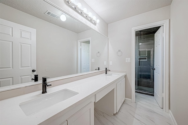 bathroom with vanity, a shower with shower door, and a textured ceiling