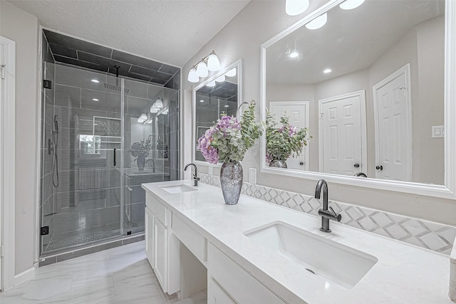 bathroom featuring vanity, a shower with door, and a textured ceiling