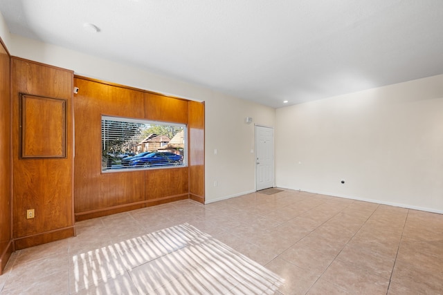 unfurnished room with wood walls and light tile patterned floors