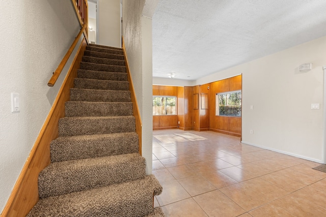 staircase with tile patterned flooring and a textured ceiling