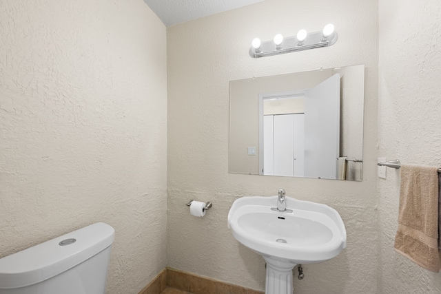 bathroom featuring sink, toilet, and a textured ceiling