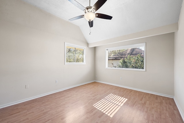 spare room with a textured ceiling, ceiling fan, vaulted ceiling, and light wood-type flooring