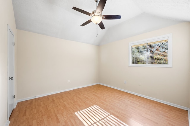 empty room featuring light hardwood / wood-style floors, vaulted ceiling, and ceiling fan