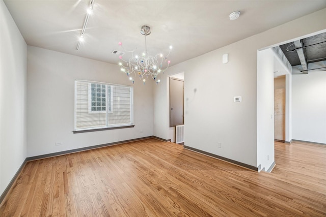 interior space featuring rail lighting, light hardwood / wood-style floors, and a notable chandelier