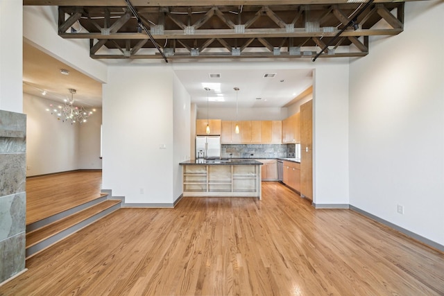 kitchen with white fridge with ice dispenser, light brown cabinets, tasteful backsplash, light hardwood / wood-style floors, and pendant lighting