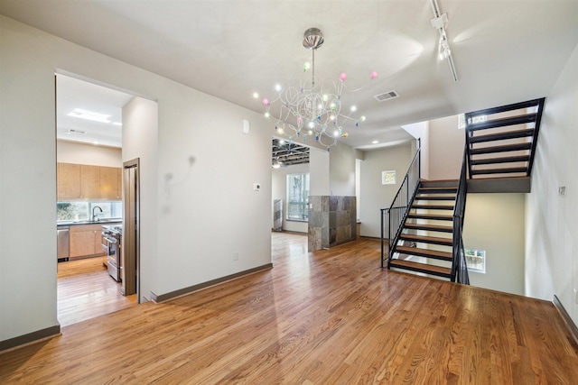 interior space featuring light wood-type flooring, track lighting, an inviting chandelier, and sink