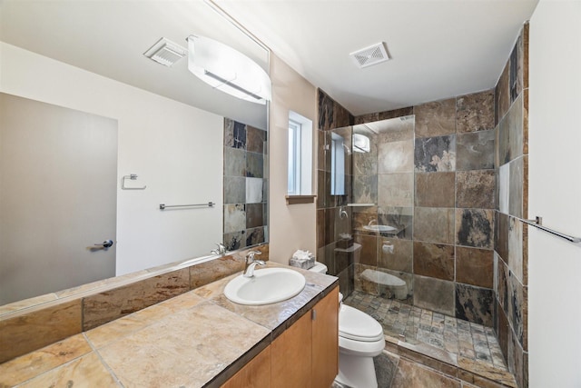 bathroom with vanity, toilet, and a tile shower