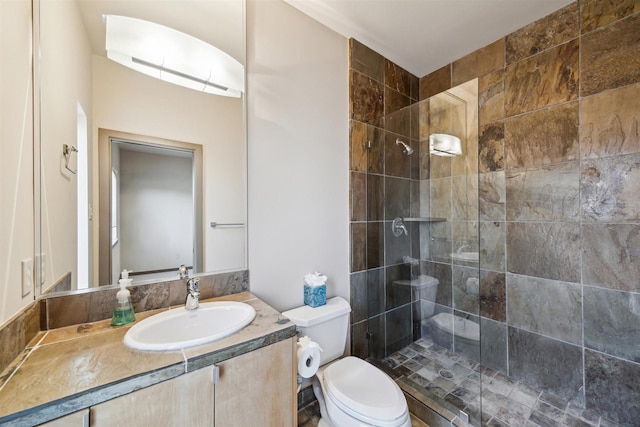 bathroom featuring vanity, toilet, and tiled shower