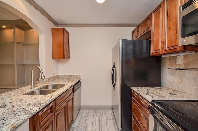 kitchen with sink, light stone counters, crown molding, decorative backsplash, and appliances with stainless steel finishes