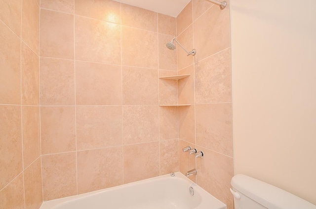 bathroom featuring tiled shower / bath combo and toilet