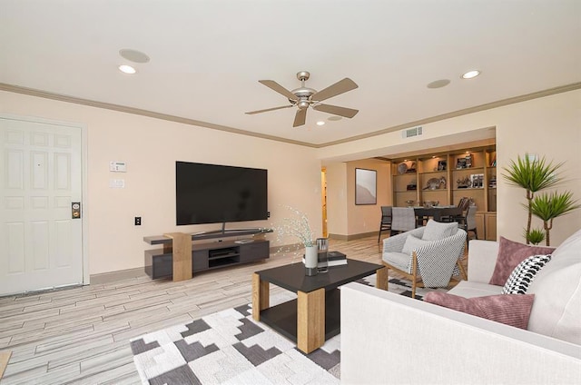 living room with ceiling fan, built in shelves, crown molding, and light hardwood / wood-style flooring