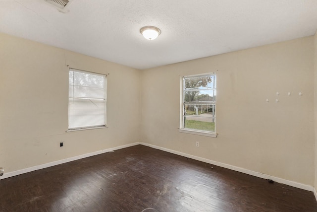 empty room with a textured ceiling and dark hardwood / wood-style floors