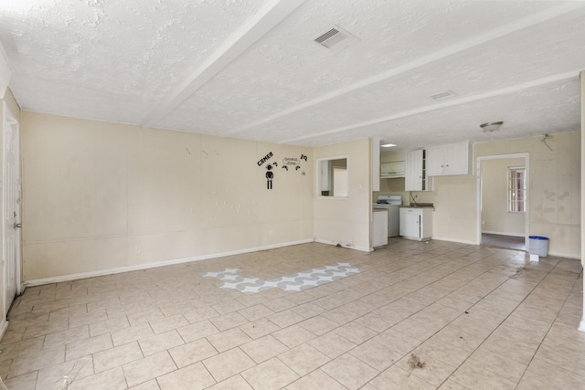 unfurnished living room with a textured ceiling and independent washer and dryer