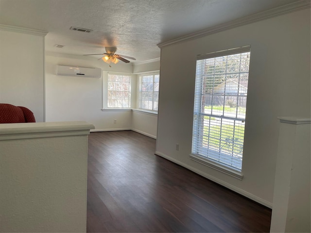 unfurnished room with ceiling fan, dark hardwood / wood-style floors, a wall unit AC, a textured ceiling, and ornamental molding