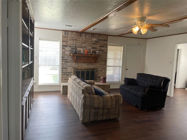 living room with crown molding, a brick fireplace, ceiling fan, a textured ceiling, and dark hardwood / wood-style flooring