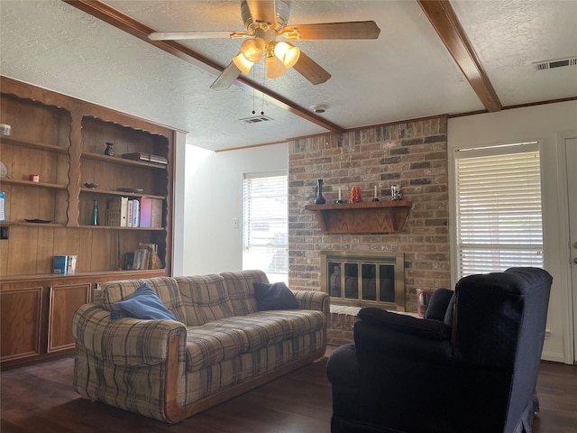 living room featuring beam ceiling, ceiling fan, dark hardwood / wood-style floors, a textured ceiling, and a fireplace