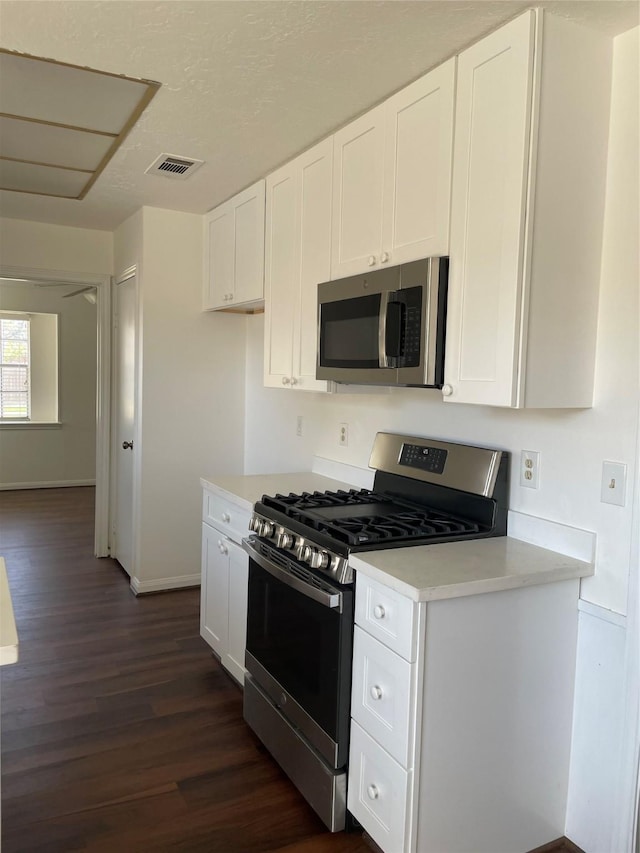 kitchen with dark hardwood / wood-style flooring, white cabinets, and stainless steel appliances