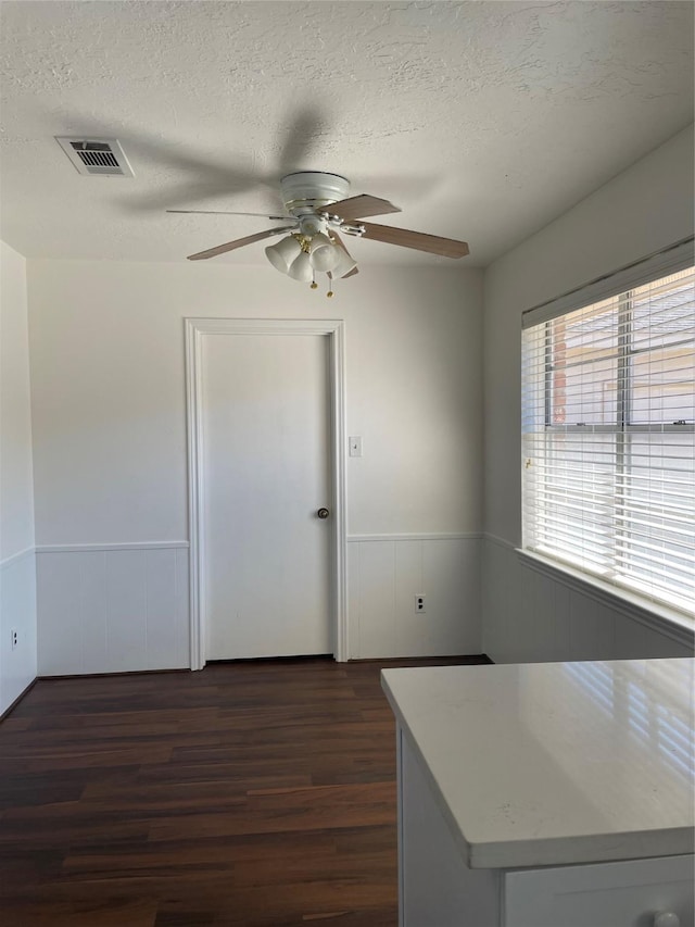 interior space with a textured ceiling, dark hardwood / wood-style floors, and ceiling fan