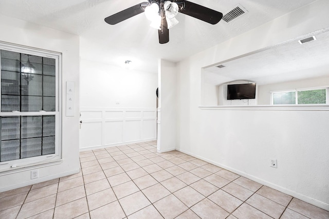 tiled empty room with a textured ceiling and ceiling fan