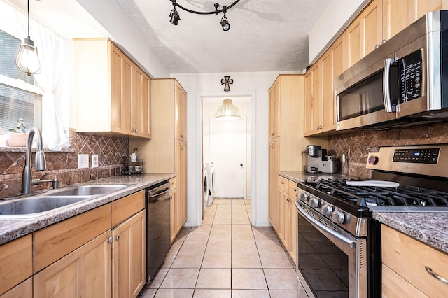 kitchen with pendant lighting, sink, washing machine and dryer, a textured ceiling, and stainless steel appliances