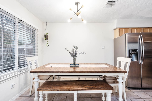 dining room featuring a chandelier, light tile patterned floors, and a textured ceiling