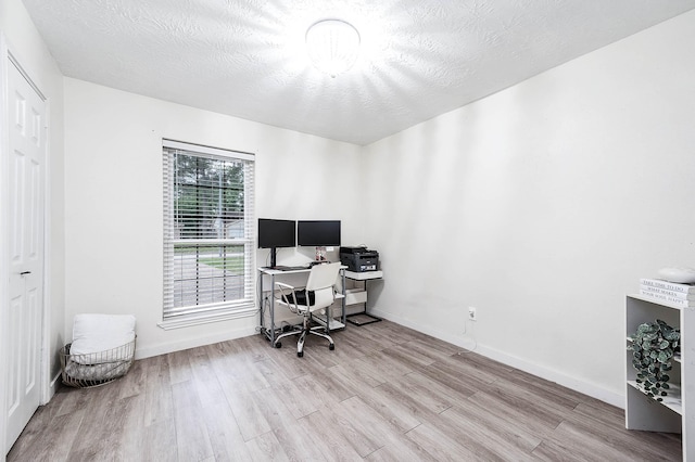 home office with light hardwood / wood-style flooring and a textured ceiling