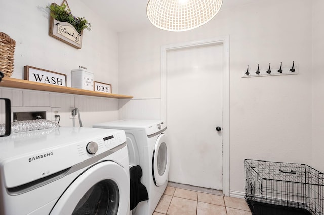 clothes washing area with washer and clothes dryer, a notable chandelier, and light tile patterned floors