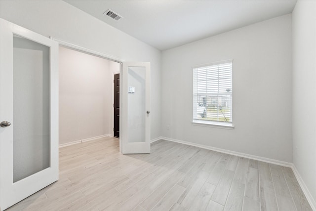 unfurnished room featuring french doors and light wood-type flooring