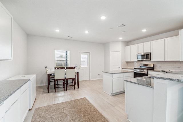 kitchen with sink, a center island, stone countertops, white cabinets, and appliances with stainless steel finishes