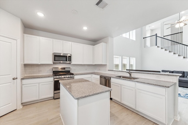 kitchen with stainless steel appliances, white cabinetry, and sink