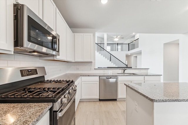 kitchen featuring white cabinets, light stone counters, sink, and appliances with stainless steel finishes