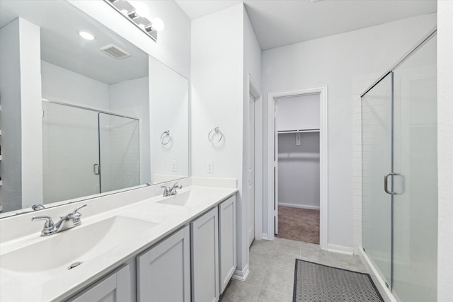 bathroom with a shower with door, vanity, and tile patterned flooring