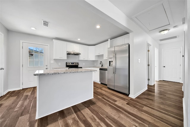 kitchen with light stone countertops, white cabinetry, a center island, and stainless steel appliances